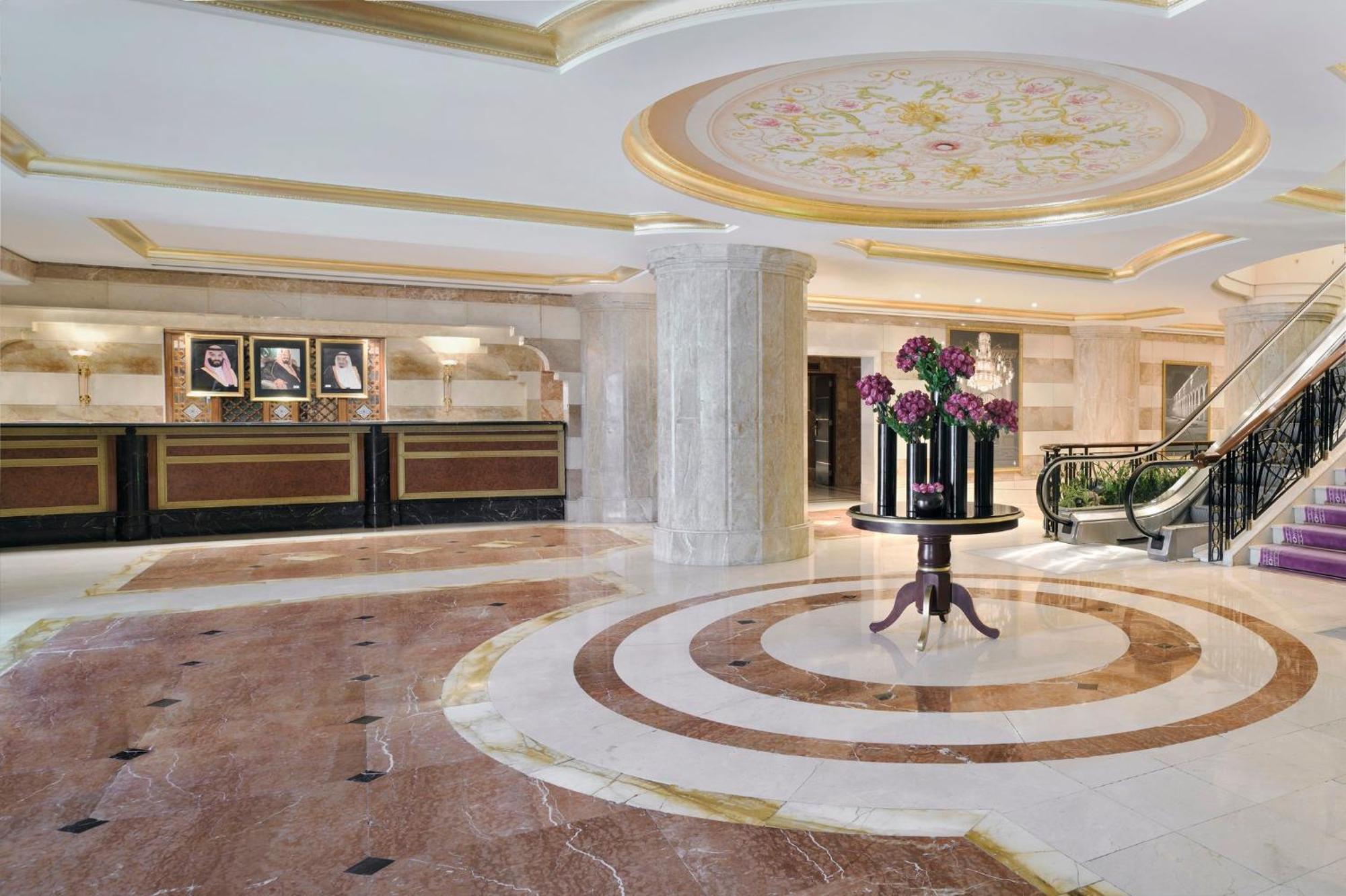 Intercontinental Dar Al Iman Madinah By Ihg Hotel Medina Exterior foto The photo shows a luxurious hotel lobby. The space features elegant marble flooring with circular designs, complemented by a large, decorative ceiling. In the center, there is a round table adorned with a floral arrangement. Behind the table, a recep