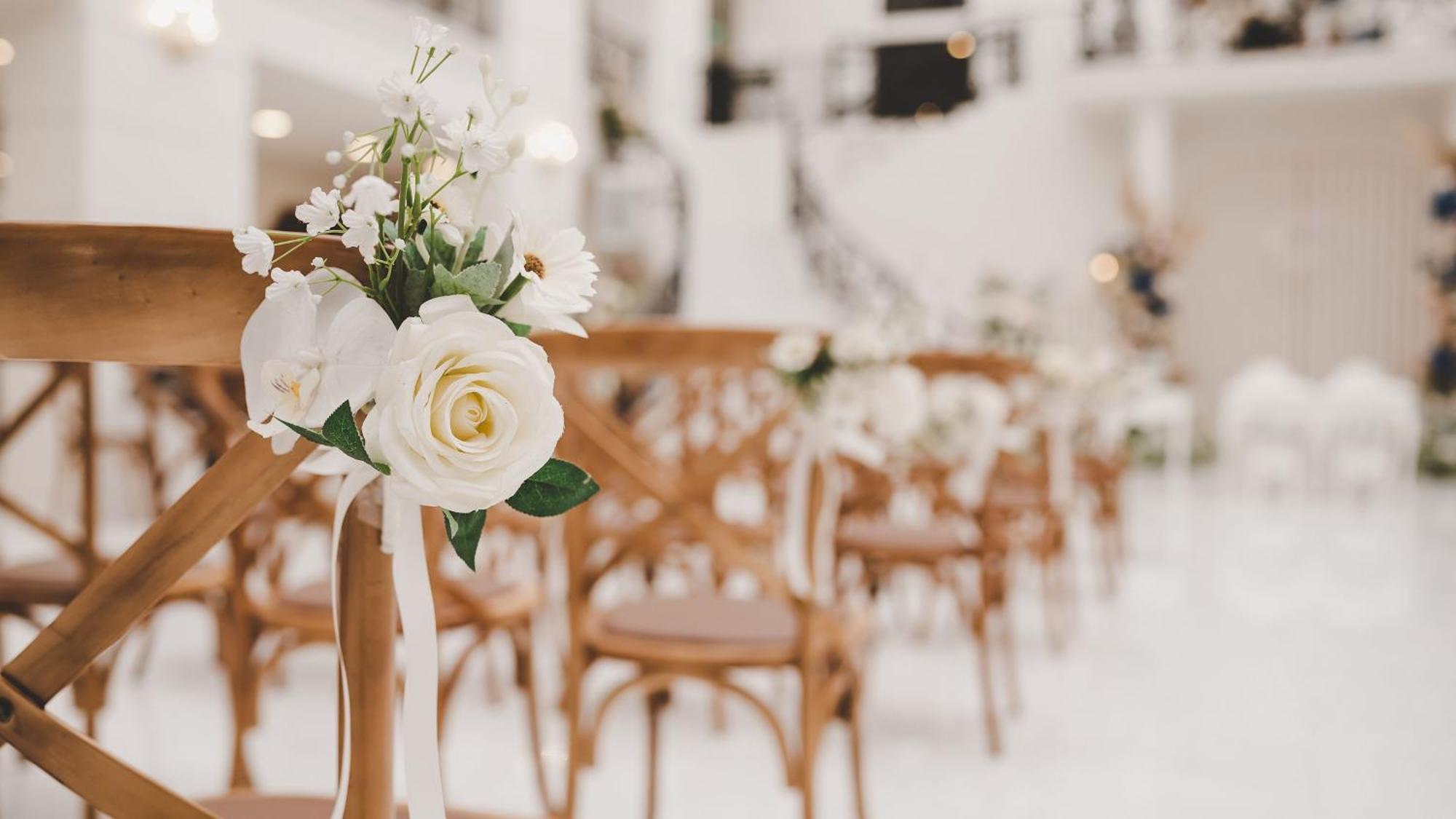 Intercontinental Dar Al Iman Madinah By Ihg Hotel Medina Exterior foto The photo showcases a beautifully arranged event space, likely set up for a wedding or special occasion. In the foreground, wooden chairs are neatly lined up, some adorned with decorative floral arrangements. The flowers include white roses and small