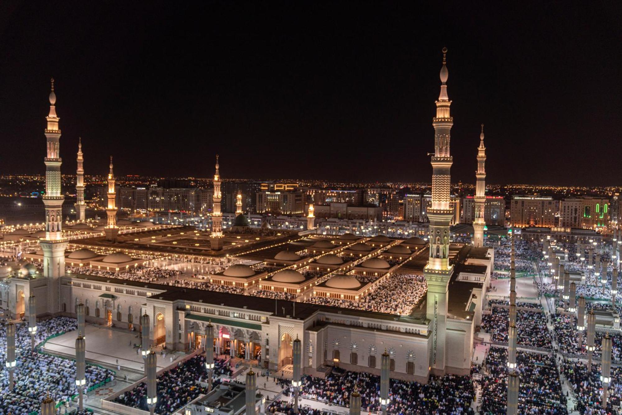 Intercontinental Dar Al Iman Madinah By Ihg Hotel Medina Exterior foto The photo shows a panoramic view of a large mosque complex illuminated at night. It features tall minarets with lights, a vast courtyard filled with people, and a beautifully lit architectural design. The overall ambiance suggests a significant space