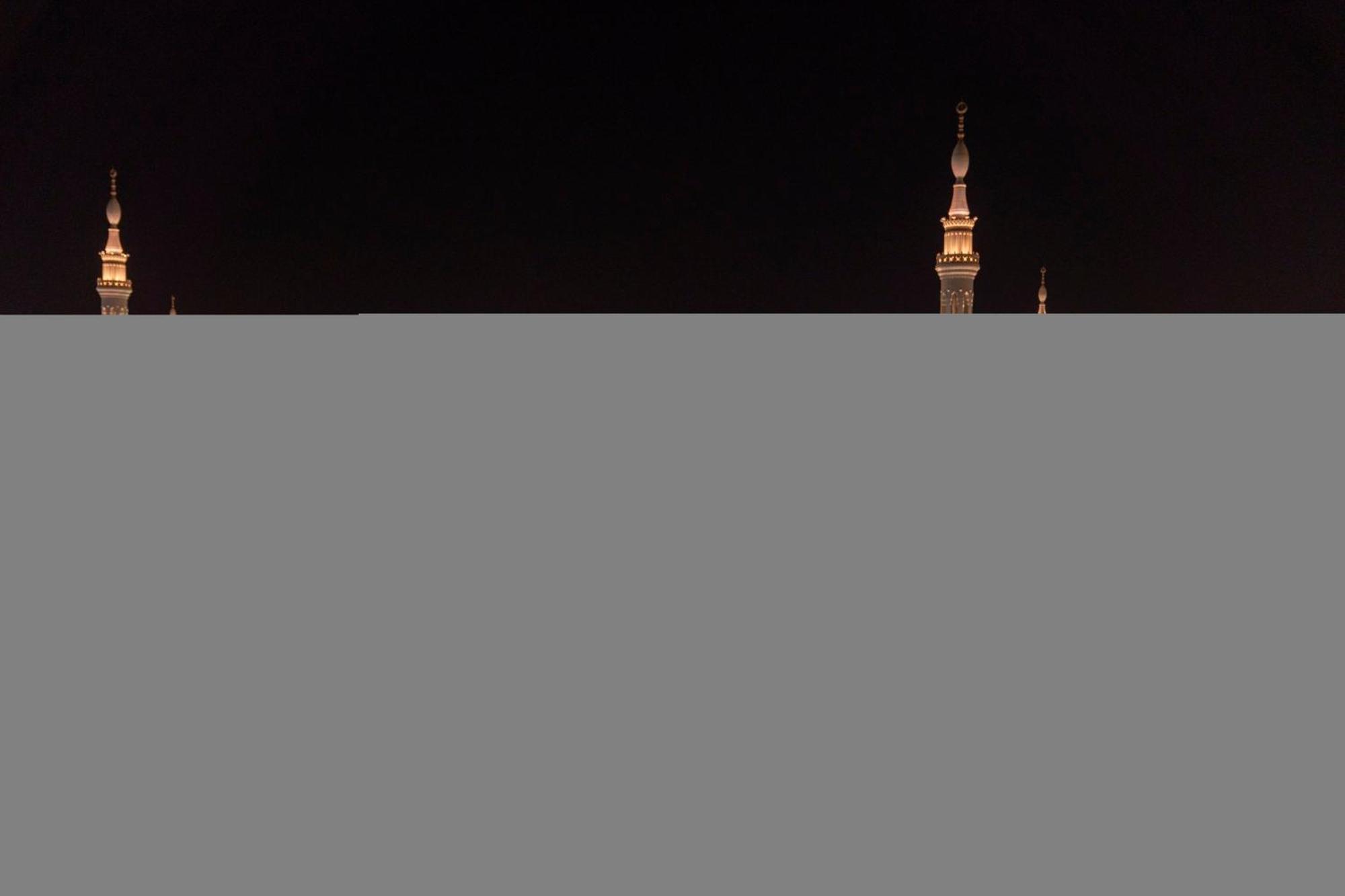 Intercontinental Dar Al Iman Madinah By Ihg Hotel Medina Exterior foto The image appears to show a night scene featuring tall structures with pointed tops, likely minarets, illuminated against a dark background. The lighting creates a striking contrast, highlighting the architectural details of the structures. The overa